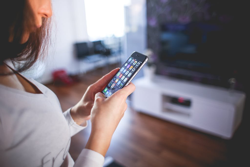 Woman browsing smartphone indoors, highlighting modern technology and communication in a cozy home setting.