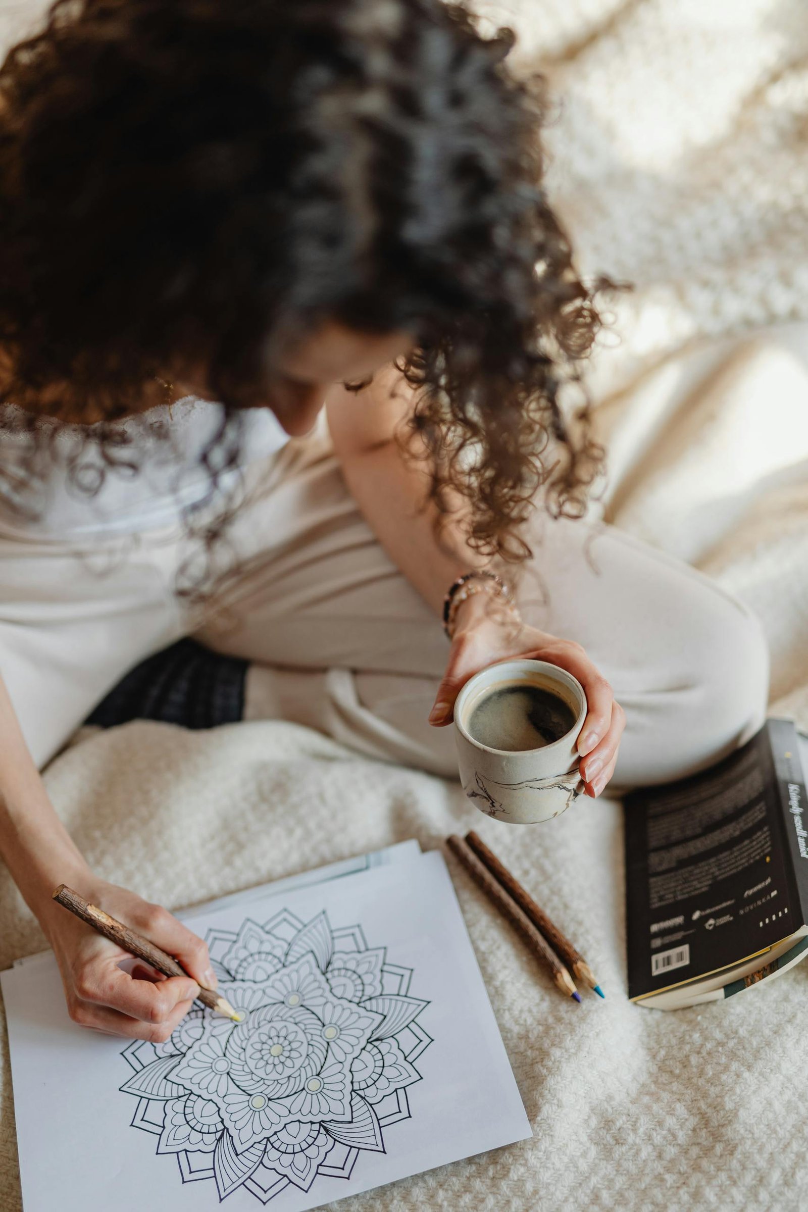 Woman enjoying a relaxing moment with a coloring book and coffee, enhancing creativity and mindfulness.