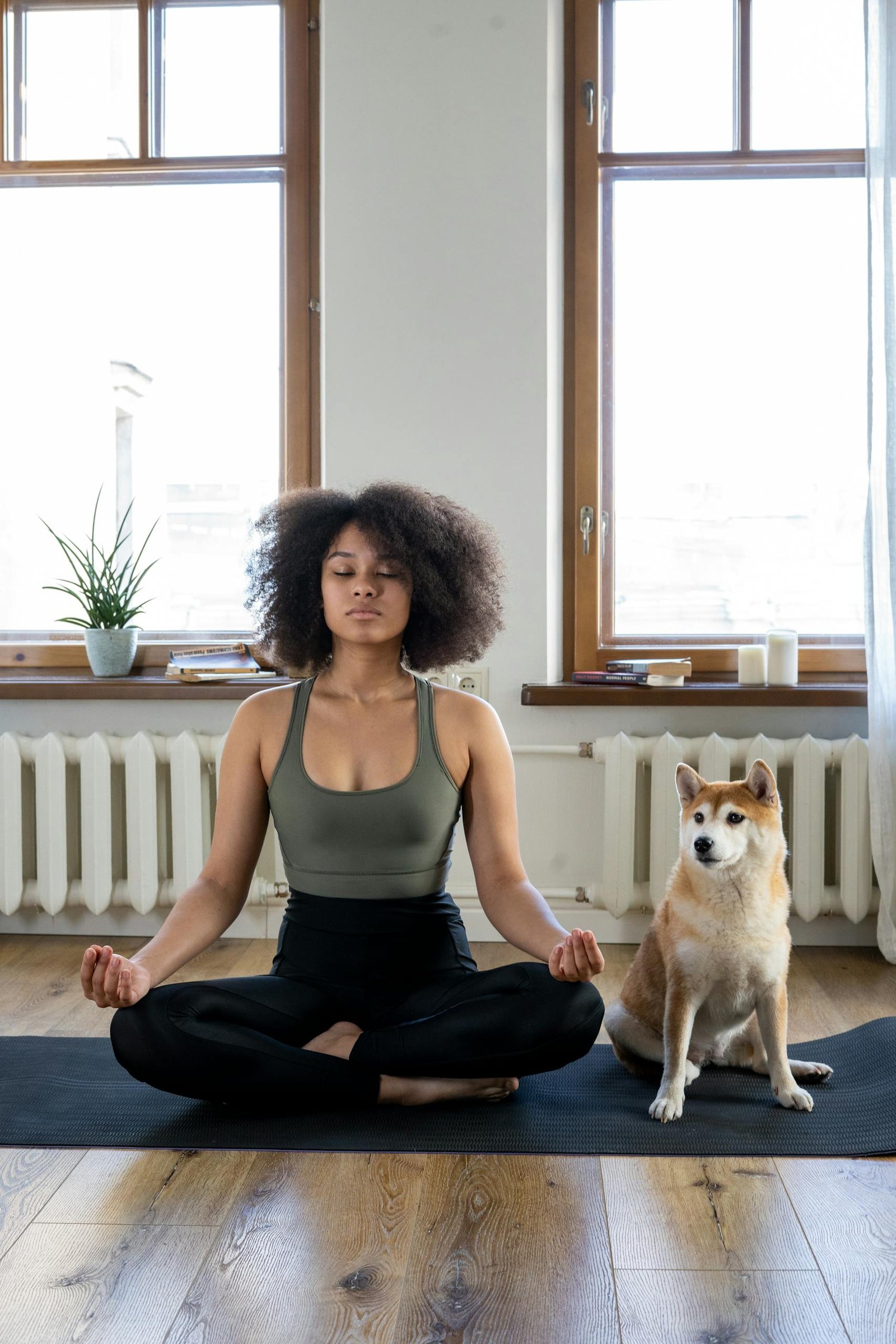 A woman practices yoga meditation at home with her dog, creating a calm and peaceful environment.